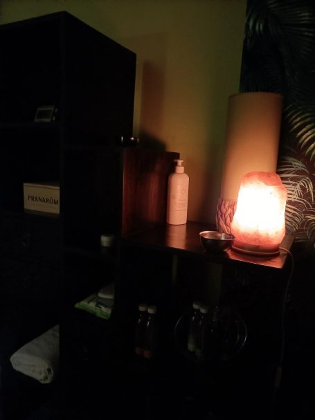 Étagère avec vase, bouteille et lampe en bois illuminée dans un coin sombre.